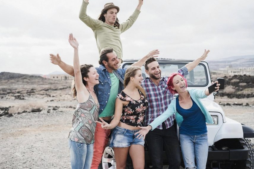 Group of friends celebrating next to a white 4WD in the Australian outback